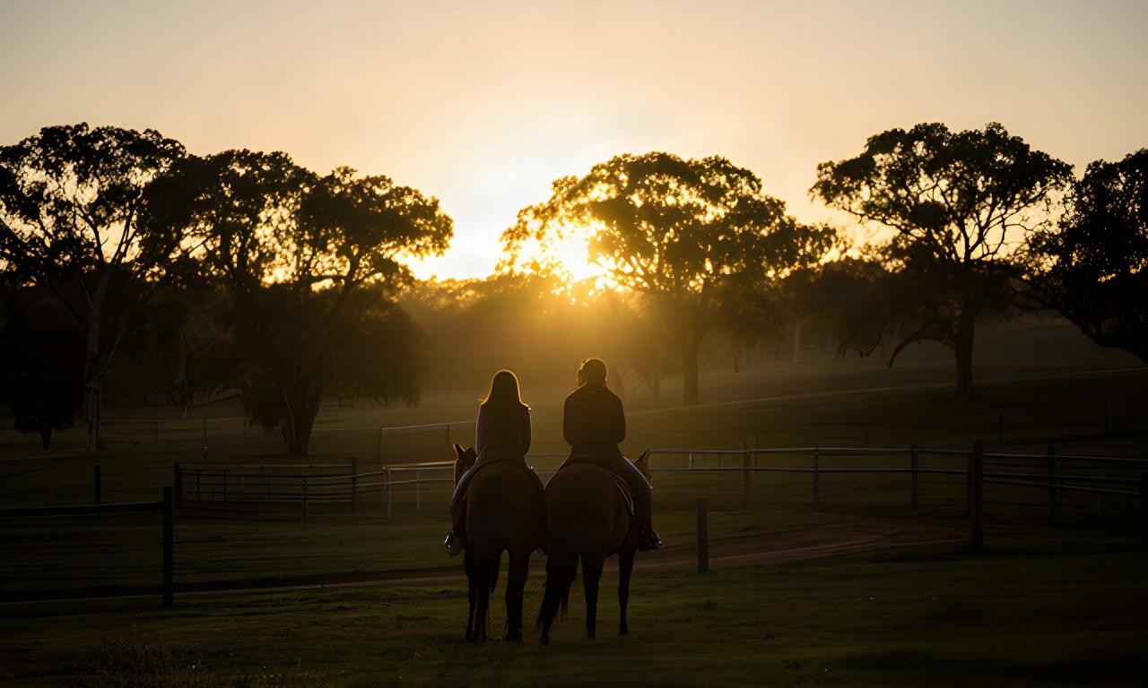 Two riders looking across a Riverina paddock as the sun lowers behind the trees